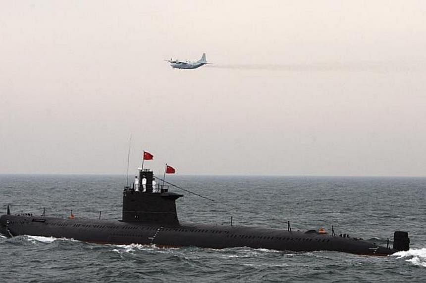 A 2009 file photo shows a military aircraft flying past a Chinese Navy submarine in Qingdao, Shandong province. Experts have dismissed a South China Morning Post report on so-called supersonic submarine technology being developed by China. -- PHOTO: 