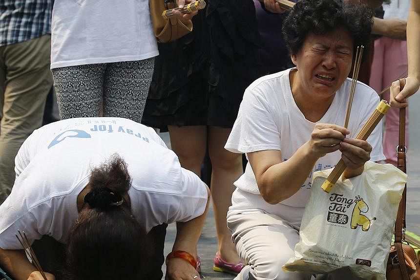 Family members of passengers aboard the missing Malaysia Airlines flight MH370 cry as they burn incense to pray at Yonghegong Lama Temple in Beijing on June 15, 2014. -- PHOTO: REUTERS