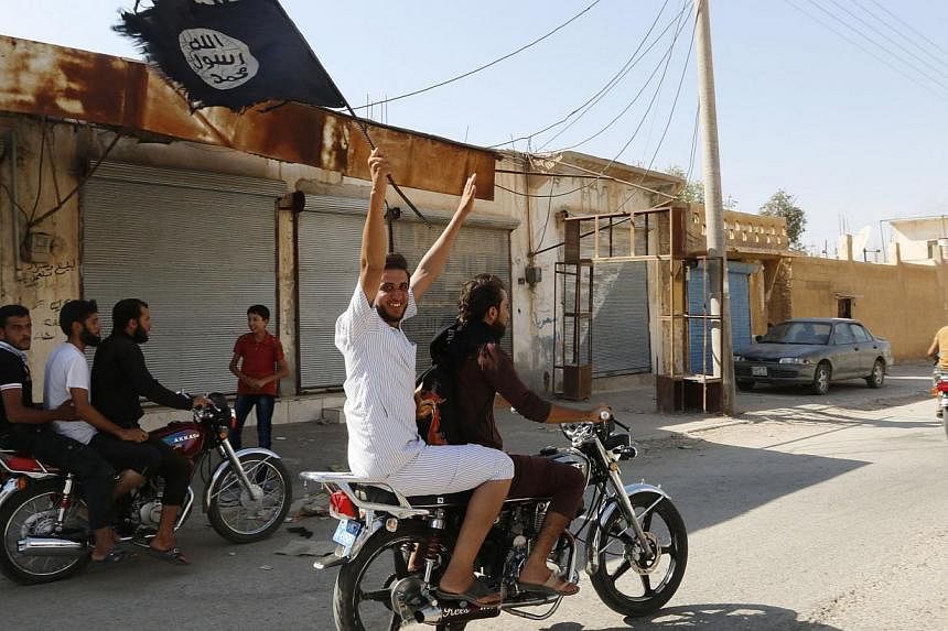A resident of Tabqa city touring the streets on a motorcycle waves an Islamist flag in celebration after Islamic State militants took over Tabqa air base, in nearby Raqqa city on Aug 24, 2014. -- PHOTO: REUTERS