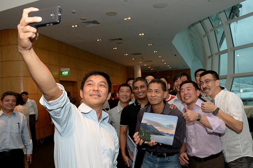Manpower Minister Tan Chuan-Jin snaps a selfie with former Singapore Armed Forces colleagues. Mr Tan has raised more than $900,000 for four charities after launching a 178-page book of his travel photos. -- ST PHOTO: DESMOND WEE&nbsp;