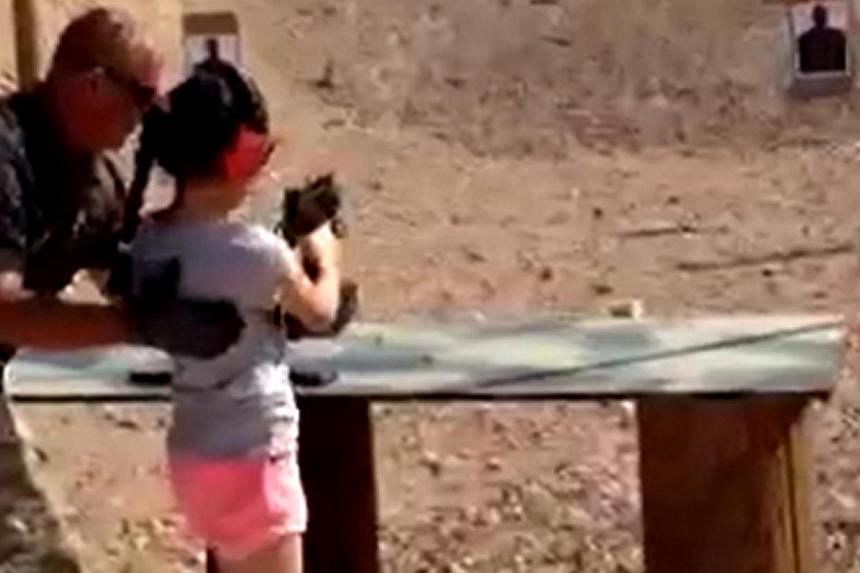 Shooting instructor Charles Vacca stands next to a 9-year-old girl at the Last Stop shooting range in White Hills, Arizona near the Nevada border on Aug 25, 2014, in this still image taken from video courtesy of the Mohave County Sheriff's Office. --