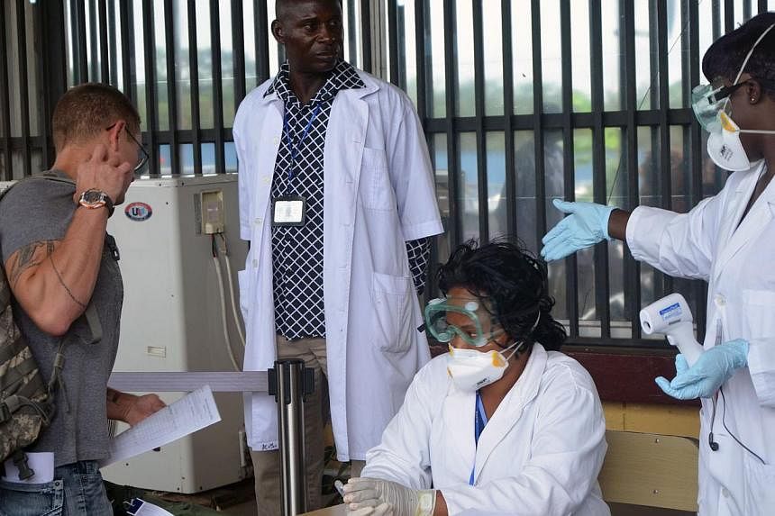 Health agents check a passenger leaving Liberia at the Roberts International Airport near Monrovia on August 27, 2014. Ebola-hit nations met for crisis talks on August 28, 2014 as the death toll topped 1,500 and the World Health Organisation warned t