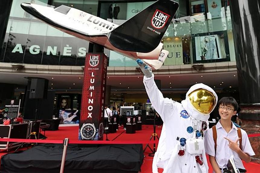 Student Elliott Chow (right) poses with a model dressed as an astronaut in front of a space shuttle model. -- ST PHOTO:&nbsp;NEO XIAOBIN