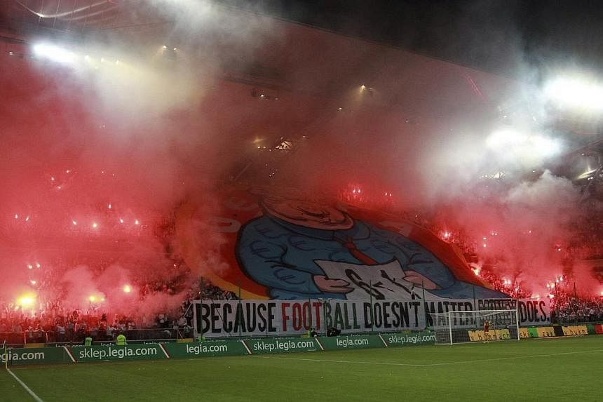 A giant banner of a pig displayed by Legia Warsaw fans is seen amid flares after the Polish club was ejected from the Champions League, during their Europa League play-off match against Kazakhstan's Aktobe in Warsaw on Aug 28, 2014. -- PHOTO: REUTERS