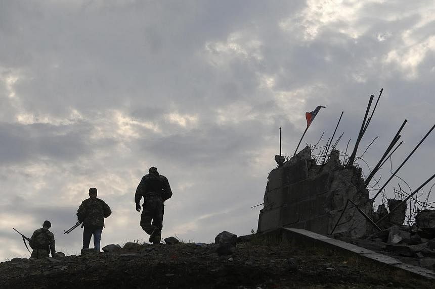 &nbsp;Pro-Russian separatists walk at a destroyed war memorial on Savur-Mohyla, a hill east of the city of Donetsk on Aug 28, 2014. -- PHOTO: REUTERS