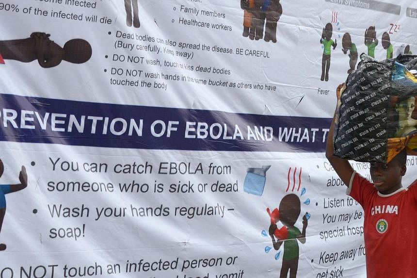 A boy walks past a banner informing about the Ebola virus near the entrance of the port of Monrovia, Liberia, on Aug 29, 2014. -- PHOTO: AFP