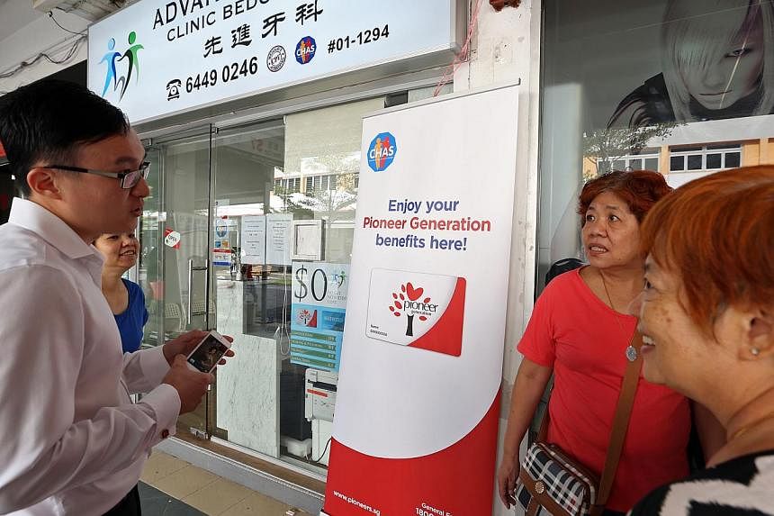 (Left) Dental Surgeon Chua Chew Kiat Simon Jude explains the CHAS scheme to seniors (second from right) Gan Bee Yan, 60, and (right) Ang Ng Tee, 65, on Aug 29, 2014. From Monday, Sept 1, all pioneer generation members will be placed on CHAS, allowing