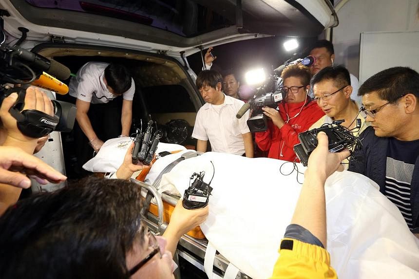 Policemen transport a stretcher with a body believed to be that of Yoo Byung Eun, who headed the family that owned the operator of the Sewol ferry that capsized in April, killing more than 300 people, into an ambulance at a hospital in Suncheon on Ju