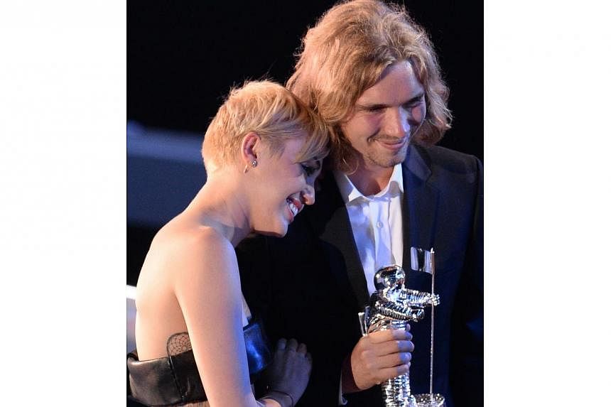 Jesse Helt (right) accepting the Video of the Year award with singer Miley Cyrus for her song Wrecking Ball on stage at the MTV Video Music Awards on August 24, 2014 in California. Helt was chosen by Cyrus to accept the award in an effort to draw att