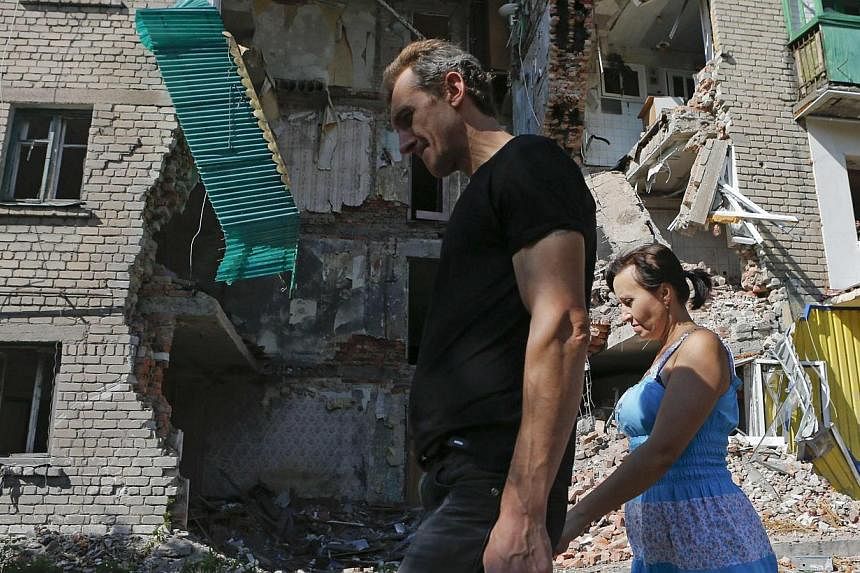 People walk past a building damaged by shelling in Snizhne, in the Donetsk region of Ukraine on August 29, 2014. The IMF signed off on its first review of Ukraine’s US$17 billion (S$21 billion) loan programme on Friday, but warned risks loomed ahea