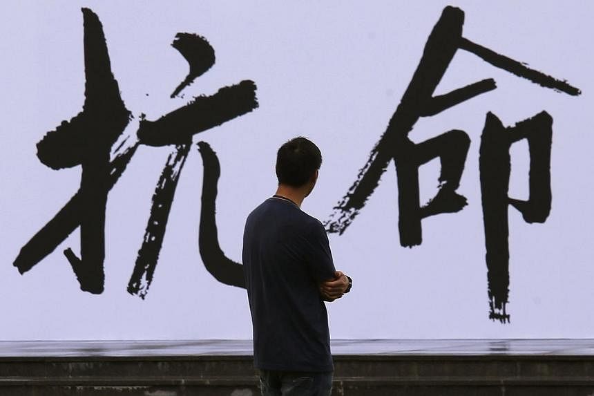 A pro-democracy activist looks at a backdrop with Chinese characters that read "disobedience", built for an Occupy Central civil disobedience campaign, near the financial Central district in Hong Kong on Aug 31, 2014. The former British colony is poi