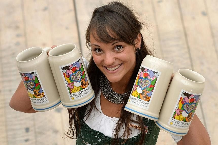 A girl presents the new Oktoberfest beer festival mug in an Oktoberfest tent in Munich, southern Germany, on Aug 21, 2014.&nbsp;Bakers in Bavaria are threatening to go on strike during Germany's famed Oktoberfest over a pay dispute, depriving beer fe
