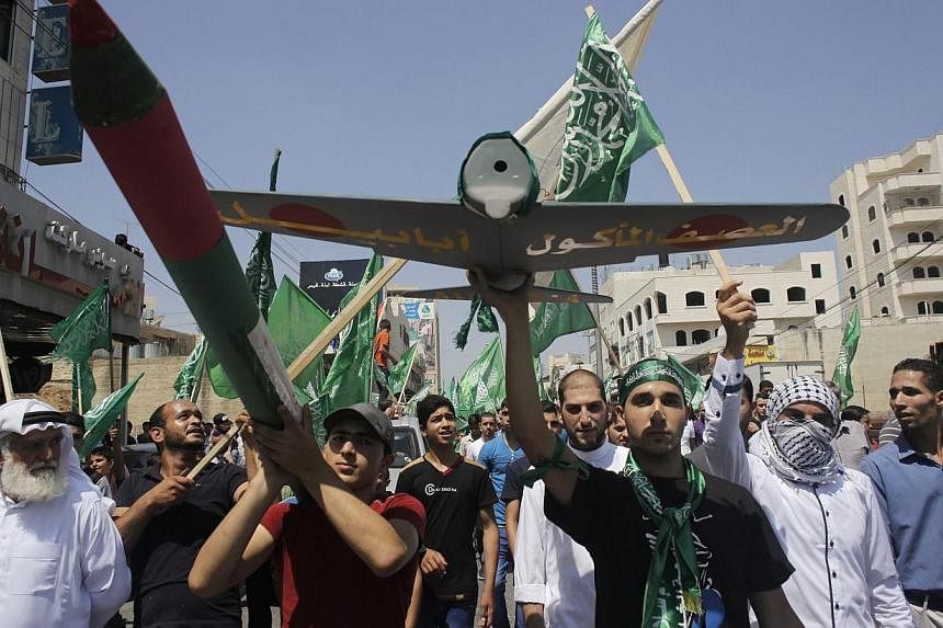 Palestinians hold a mock rocket and a model of a Hamas-made drone during a rally celebrating what they said was a victory by Palestinians in Gaza over Israel, following a ceasefire, in the West Bank city of Hebron on Aug 29, 2014. -- PHOTO: REUTERS