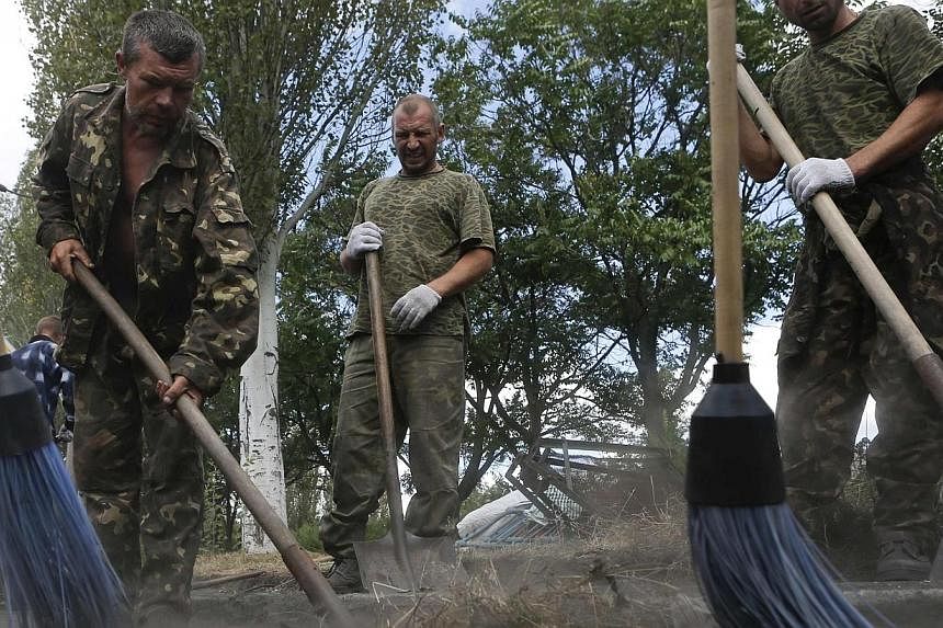 Prisoners-of-war, who are Ukrainian servicemen captured by pro-Russian separatists, clean a street in Snizhne (Snezhnoye), Donetsk region, on Aug 29, 2014.&nbsp;Ukraine has handed over a group of captured Russian paratroops and Russia has returned 63