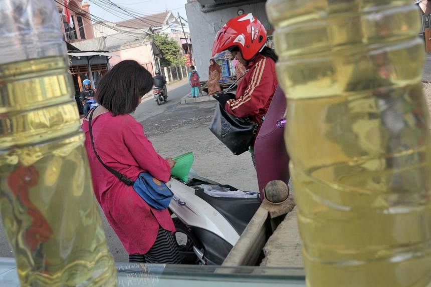This picture taken on August 29, 2014 shows a motorist (right) filling up her motorcycle with subsidized gasoline at a kiosk in Jakarta. Just weeks before Joko Widodo takes office in Indonesia, a ham-fisted attempt by the outgoing government to tackl