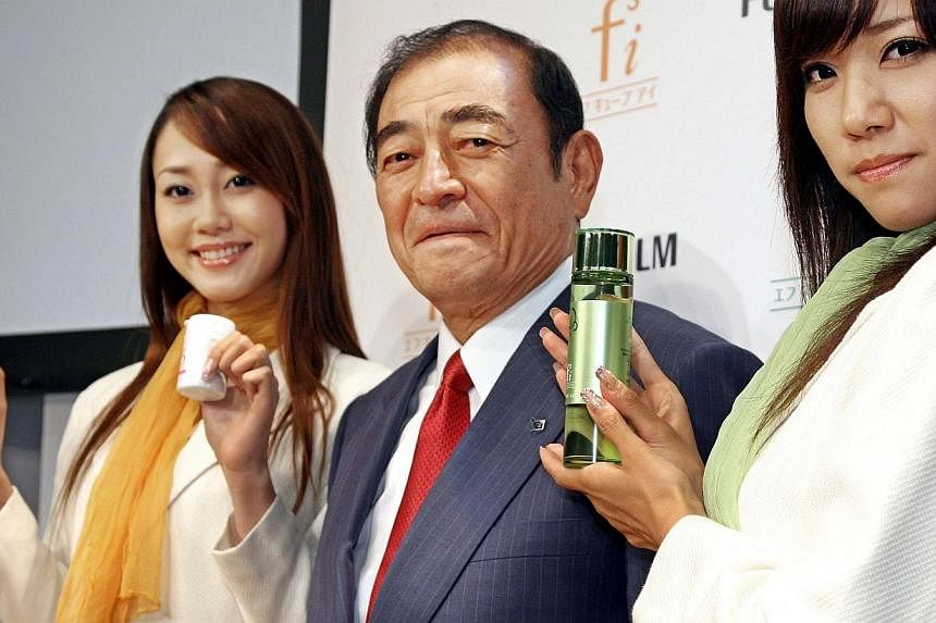 This file picture taken on September 12, 2006 shows Japan's camera giant Fujifilm CEO Shigetaka Komori (center) showing off the company's new three skin care items (R green bottles) and dietary supplements (left) in Tokyo. When Japan announced it was