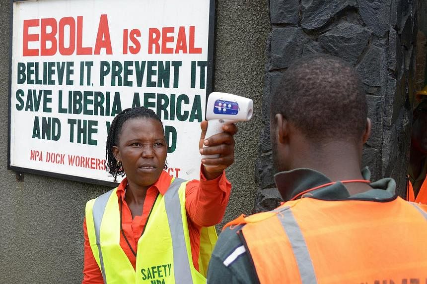 A security agent controls the temperature of a woman at the entrance of the port of Monrovia on Aug 29, 2014. -- PHOTO: AFP&nbsp;