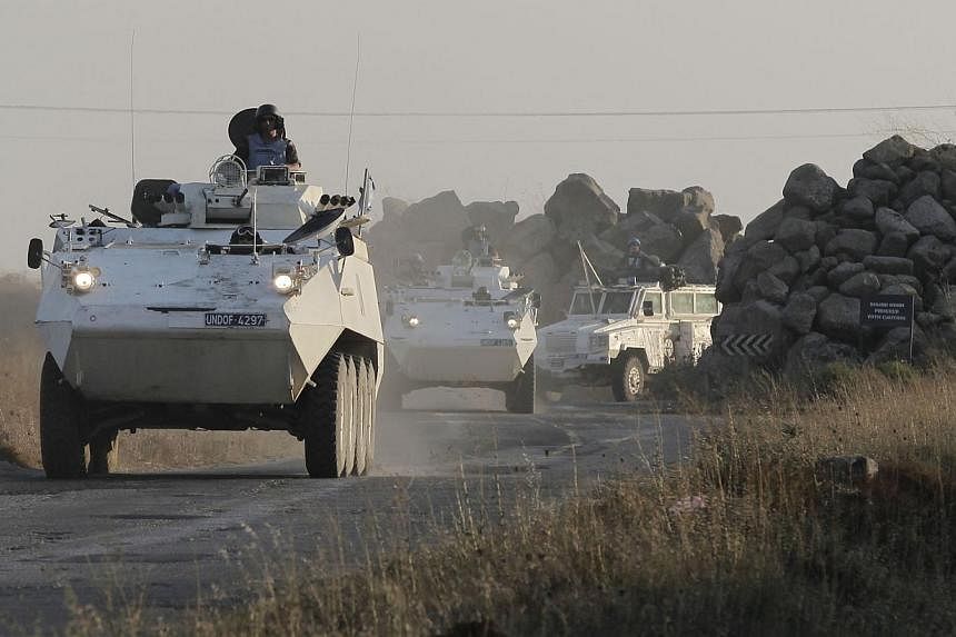 Members of the United Nations Disengagement Observer Force (UNDOF) drive their armoured vehicles in the Israeli-annexed Golan Heights near the Quneitra crossing, the only border crossing between Israel and Syria, on Aug 30, 2014. -- PHOTO: AFP