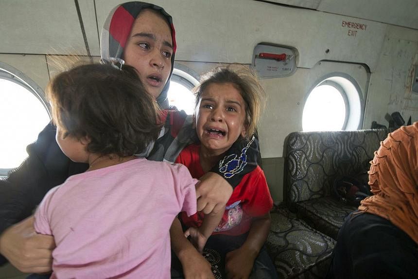 A woman and children react in a military helicopter after being evacuated by Iraqi forces from Amerli, north of Baghdad on Aug 29, 2014. -- PHOTO: REUTERS