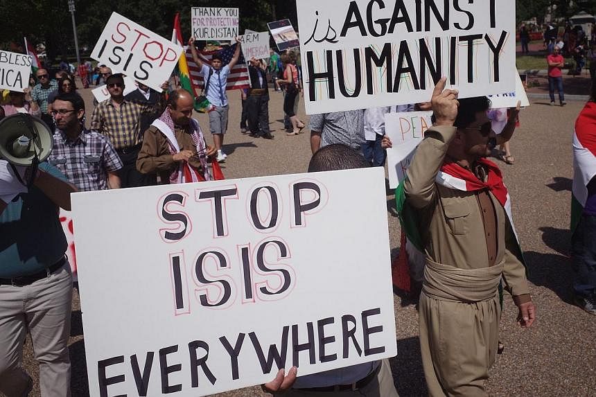 Demonstrators at a rally supporting Kurdistan hold placards protesting against the Islamic State of Iraq and Syria (ISIS) in front of the White House in Washington, DC on Aug 16, 2014. -- PHOTO: AFP&nbsp;