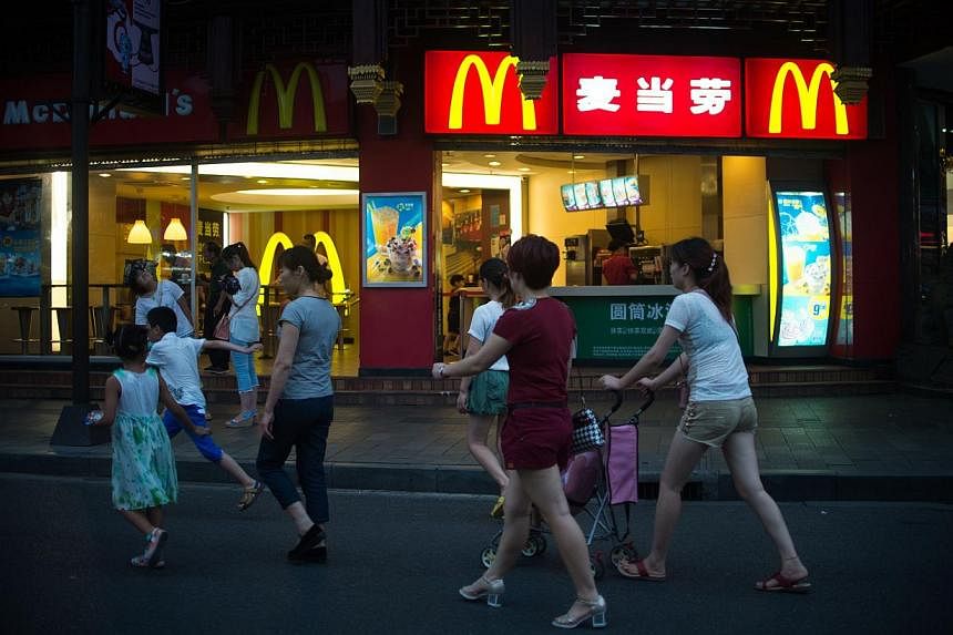 People passing by a McDonald's fast food restaurant in Shanghai on July 28, 2014.&nbsp;The Chinese authorities have formally arrested six employees from a unit of United States food supplier OSI Group over a scandal involving expired meat sold to fas