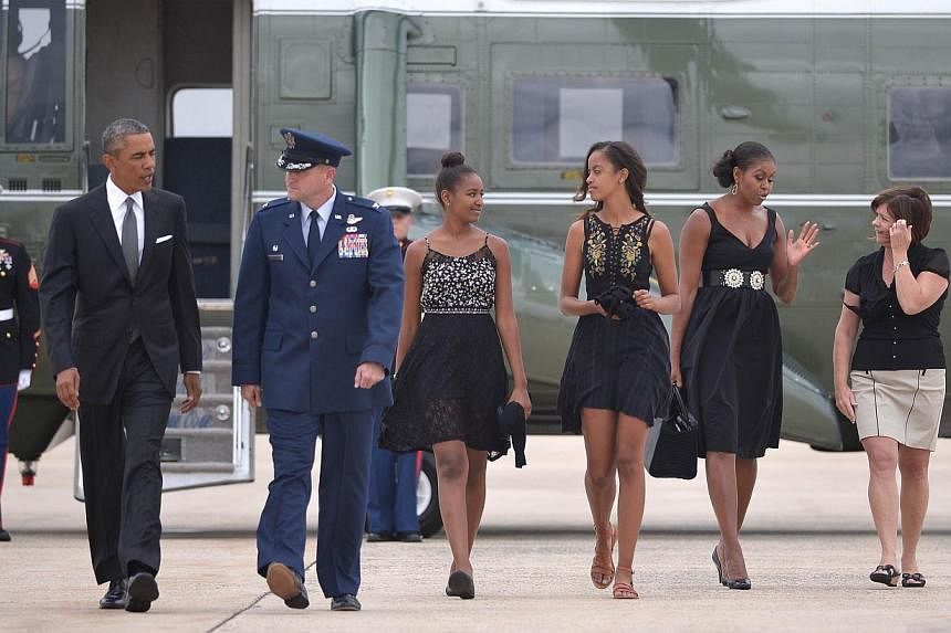 US President Barack Obama (left) and First Lady Michelle Obama (second from right) with daughters Malia (centre right) and Sasha make their way to board Air Force One before departing from Andrews Air Force Base in Maryland on August 30, 2014. Obama 