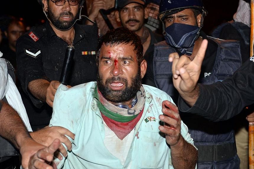 Pakistani policemen arrest an injured supporter of Canadian cleric Tahir ul Qadri following clashes with security forces near the prime minister's residence in Islamabad on Aug 31, 2014. -- PHOTO: AFP