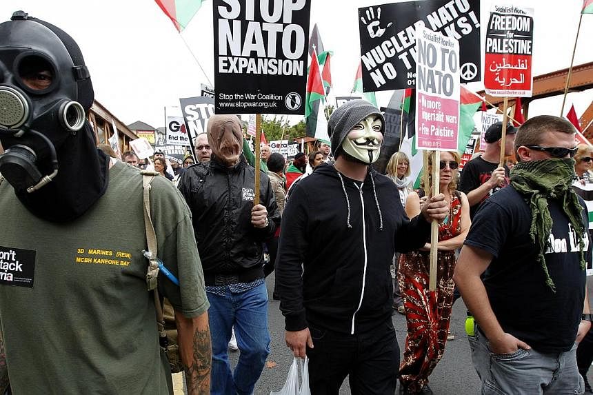 Demonstrators wearing masks join an anti-war protest march in Newport, South Wales on August 30, 2014 ahead of the upcoming Nato summit. Wales will host a gathering of international leaders as Britain hosts the Nato summit on September 4 and 5. -- PH