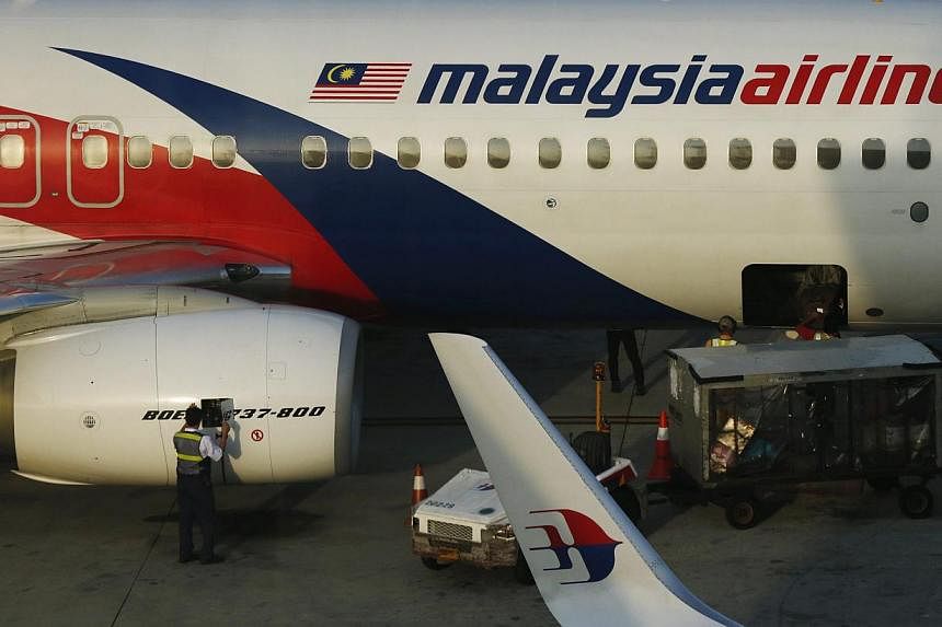 A member of ground crew works on a Malaysia Airlines Boeing 737-800 airplane on the runway at Kuala Lumpur International Airport in Sepang. -- PHOTO: REUTERS