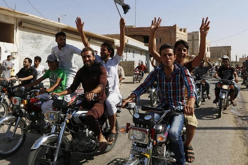 Residents of Tabqa city tour the streets on motorcycles, carrying flags in celebration after Tabqa air base fell to Islamic State militants. -- PHOTO: REUTERS