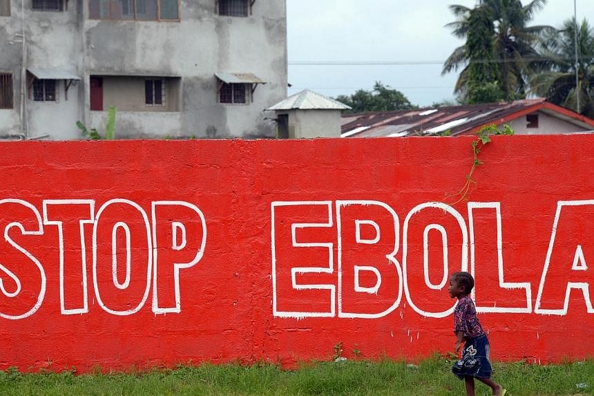 A girl walks past a slogan painted on a wall in Monrovia on Aug 31, 2014.&nbsp;Japanese researchers said Tuesday they had developed a new method to detect the presence of the Ebola virus in 30 minutes, with technology that could allow doctors to quic