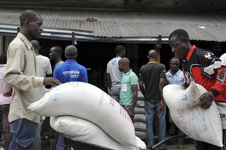Residents of West Point neighbourhood, which has been quarantined following an outbreak of Ebola, receive food rations from the United Nations World Food Programme (WFP) in Monrovia on Aug 28, 2014.&nbsp;The world's worst Ebola epidemic has put harve