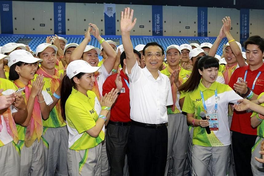 Chinese Premier Li Keqiang (centre) waves as he meets with volunteers of the 2014 Nanjing Youth Olympic Games in Nanjing, Jiangsu province on Aug 28, 2014.&nbsp;-- PHOTO: REUTERS