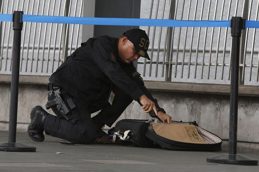 A member of the Philippine National Police's Explosive Ordinance Disposal unit examines abandoned luggage found at the entrance of Terminal 3 of the Ninoy Aquino International airport in Pasay City, Metro Manila on Sept 1, 2014. -- PHOTO: REUTERS