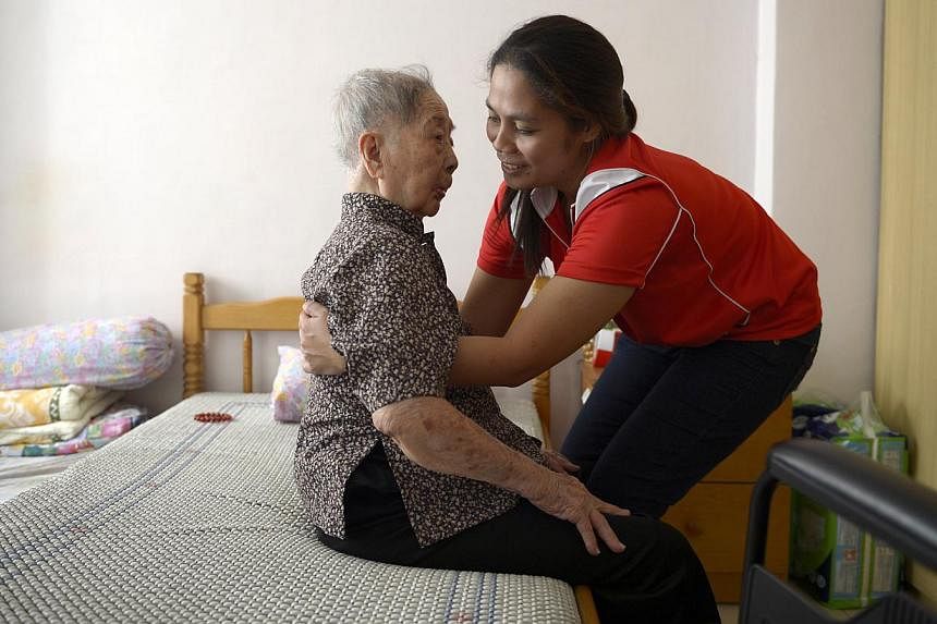 Ms Jenny Exconde (right), a care worker, is trained in a range of services to provide for all the needs of Madam Lim Yim Tee at home. -- PHOTO: ST FILE