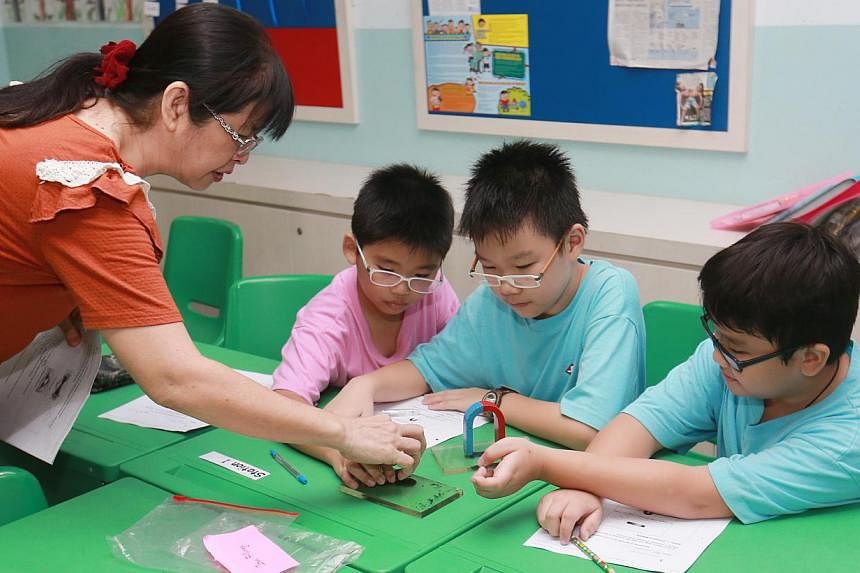 Primary school pupils with a volunteer teacher at a CDAC tuition centre at Sengkang Primary on Aug 31, 2014. -- PHOTO: ZAOBAO