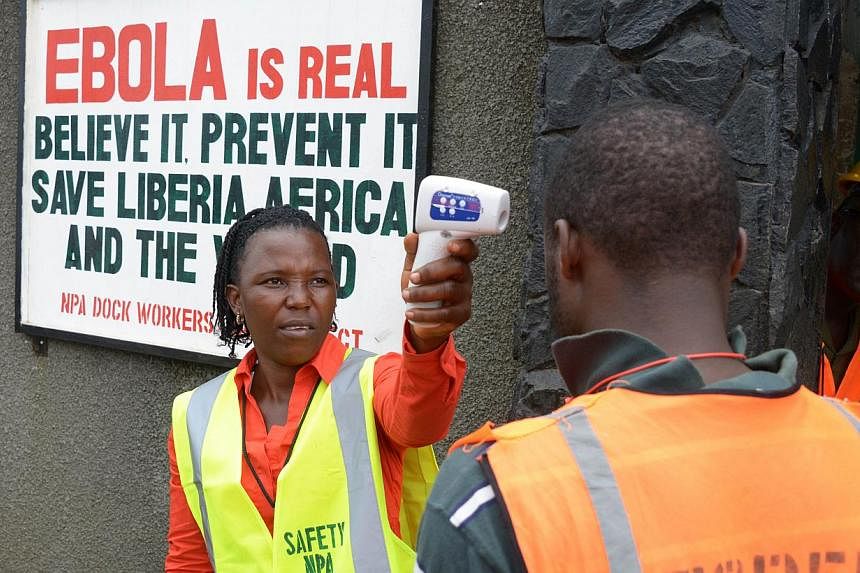 A security agent controls the temperature of a woman at the entrance of the port of Monrovia on Aug 29, 2014. -- PHOTO: AFP