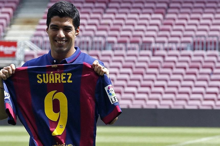 FC Barcelona's Luis Suarez holds up his jersey during his presentation at the Nou Camp stadium in Barcelona on Aug 19, 2014. -- PHOTO: REUTERS