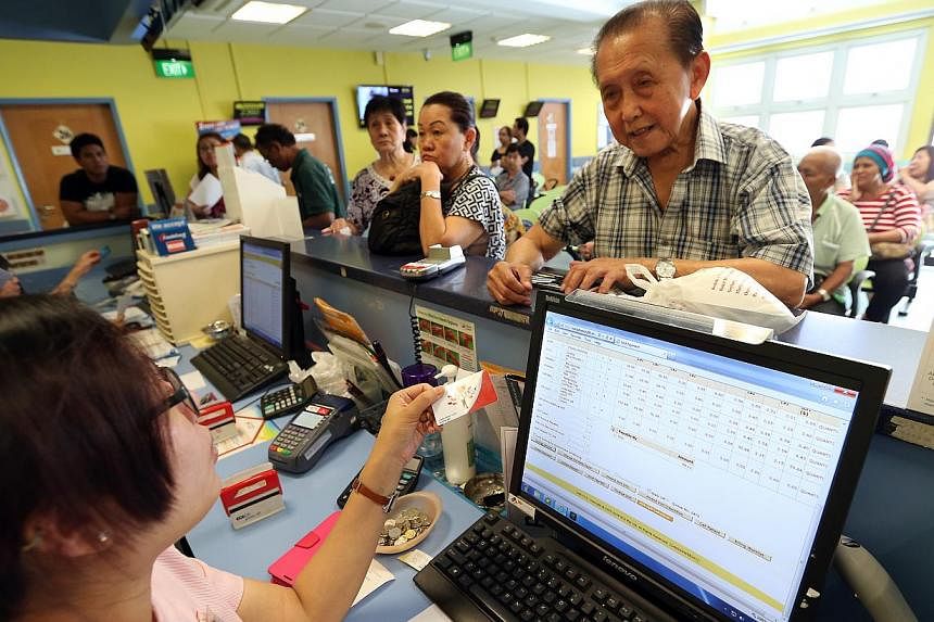 84-year-old Mr Liang Ming Chee (right) uses his Pioneer Generation card at the payment counter of Bedok Polyclinic after consultation. -- ST PHOTO: NEO XIAOBIN