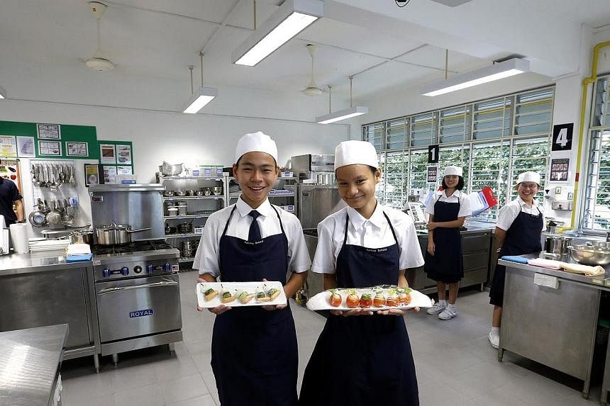 Sim Yong Meng, 14 (left) and Clarissa Lin, 14 showing off their preparation of quarl eggs and sausage cocktail in the F&amp;B training room. -- ST PHOTO:&nbsp;CHEW SENG KIM