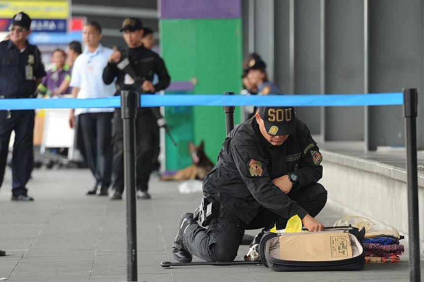 A Philippine police bomb disposal unit member inspects abondoned luggage at the departure area of the airport's terminal three in Manila on Sept 1, 2014, hours after a utility vehicle containing an "improvised explosive device" was found at the car p