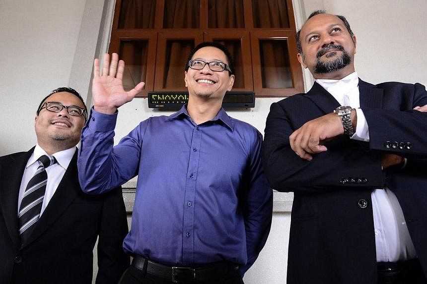 University of Malaya law lecturer Azmi Sharon (centre) waves to journalists as his lawyer Gobind Singh (right) looks on at the Sessions Court on Sept 2, 2014, after he was charged with sedition in Kuala Lumpur. -- PHOTO: AFP&nbsp;