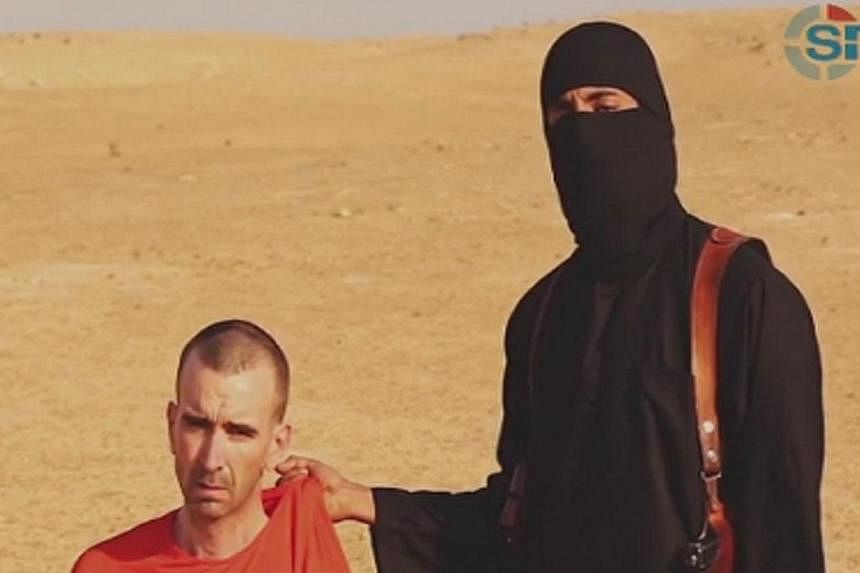 A still from a video purportedly showing threats being made to a man named as David Haines by a masked&nbsp;Islamic State (ISIS)&nbsp;fighter in an unknown location. The video was released by ISIS on Sept 2, 2014. -- PHOTO: REUTERS