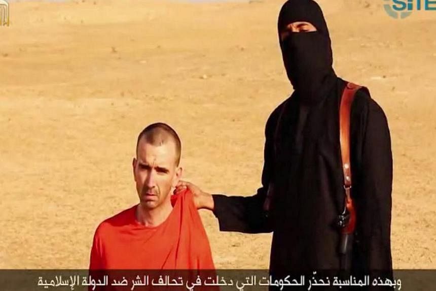 An image grab taken from a video released by the Islamic State (ISIS) and identified by private terrorism monitor SITE Intelligence Group on Sept 2, 2014, purportedly shows footage of a masked militant threatening to kill Briton David Cawthorne Haine