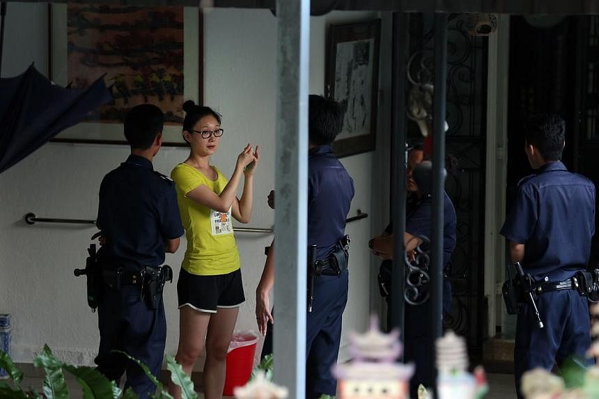 Mr Yang Yin's wife (in yellow) talking to police officers yesterday at the Gerald Crescent bungalow home of Madam Chung Khin Chun, 87. Mrs Yang, who is from China, told The Straits Times before leaving the house that Madam Chung had invited her husba