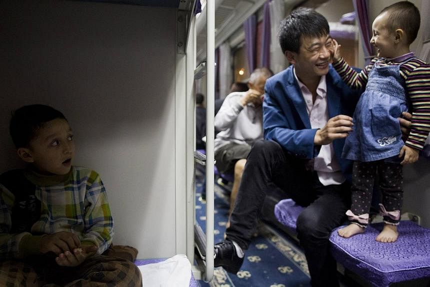 Uighur children play with a Han man on a train from Shanghai to Xingjiang, on May 14, 2014.&nbsp;The authorities are offering rewards of 10,000 yuan (S$2,000) a year to promote intermarriage in restive Xinjiang between ethnic minorities and China's d