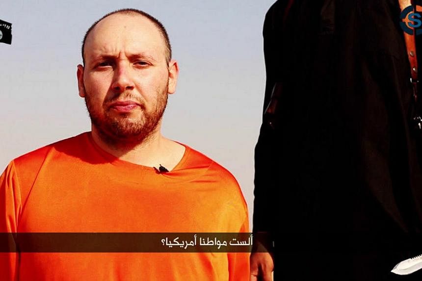A video purportedly showing US journalist Steven Sotloff kneeling next to a masked Islamic State fighter holding a knife in an unknown location in this still image from a video released by the Islamic State on Sept 2, 2014.&nbsp;The video of the exec