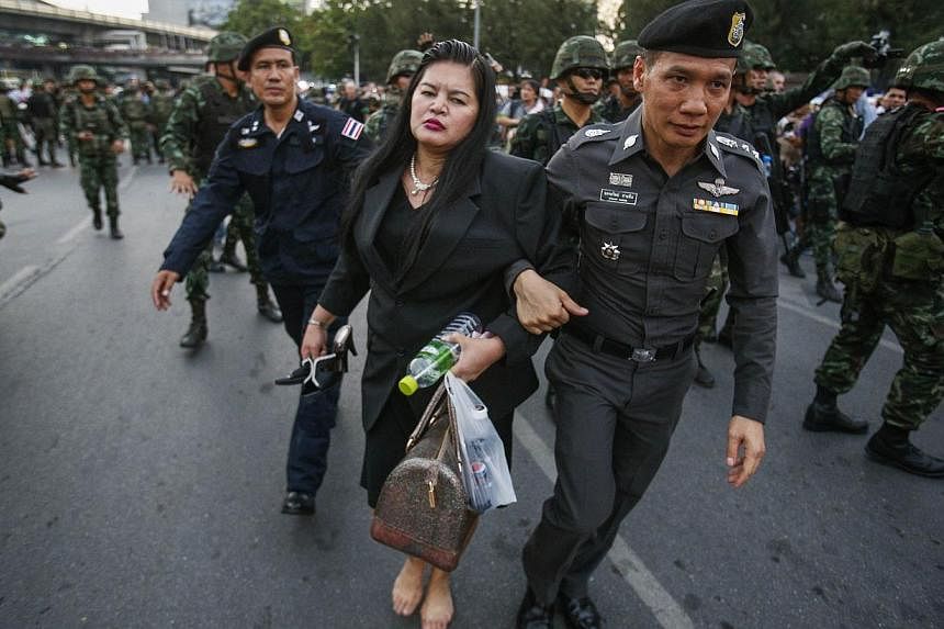 A policeman and soldiers leading a woman who showed her support for the army to safety and away from protesters against military rule at the Victory Monument in Bangkok, in this May 26, 2014 file photo.&nbsp;Since seizing power from the elected gover