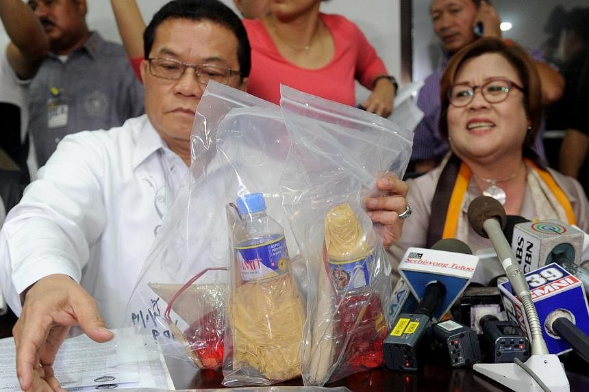 Justice Secretary Leila de Lima (right) and National Bureau of Investigation director Virgilio Mendez (left) display seized improvised firebombs and firearms in Manila on Sept 2, 2014 after three men, who were detained the day before at the airport w
