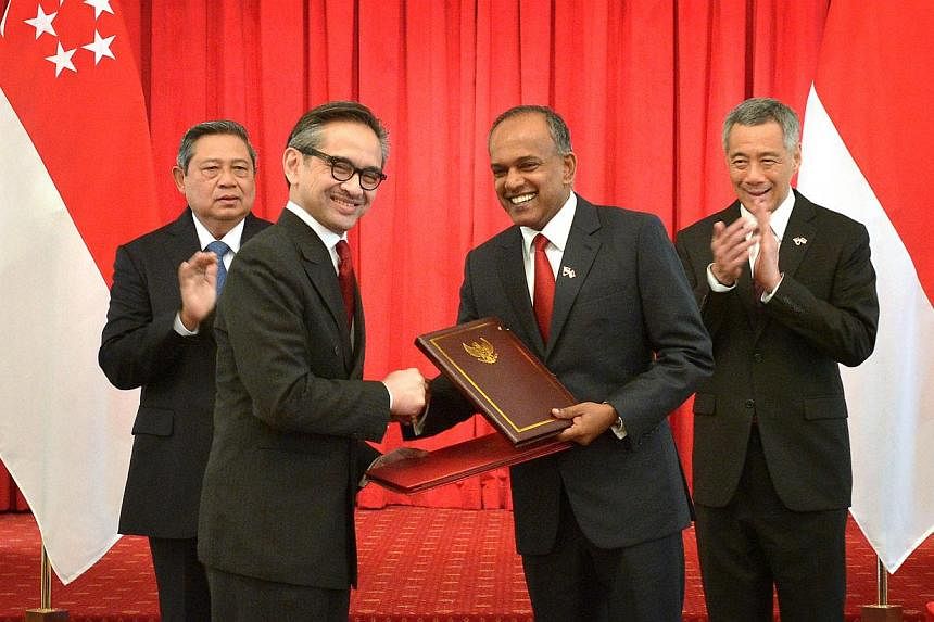 Indonesian President Susilo Bambang Yudhoyono (left) and Singapore Prime Minister Lee Hsien Loong (right) look on as Indonesian Foreign Minister Marty Natalegawa (second from left) exchanges the treaty with Singapore Foreign Minister K. Shanmugam (se